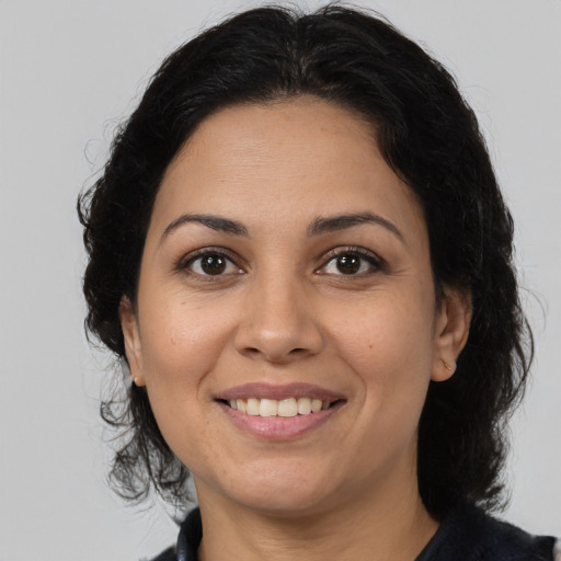 Joyful latino adult female with medium  brown hair and brown eyes