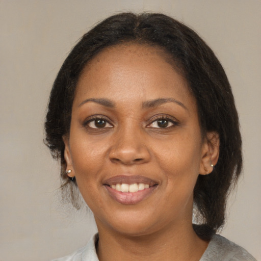 Joyful black adult female with medium  brown hair and brown eyes