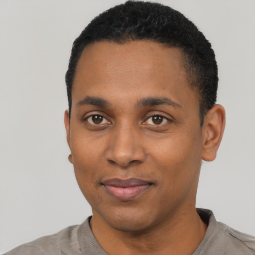 Joyful black young-adult male with short  black hair and brown eyes