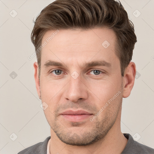 Joyful white young-adult male with short  brown hair and grey eyes