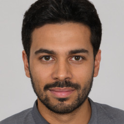 Joyful latino young-adult male with short  black hair and brown eyes