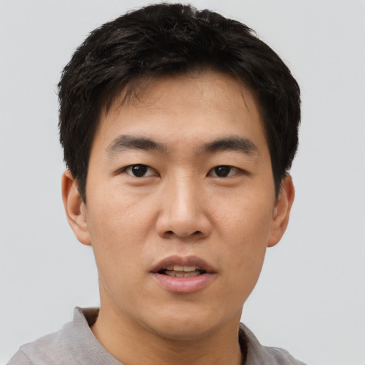 Joyful asian young-adult male with short  black hair and brown eyes