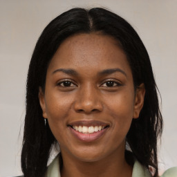 Joyful black young-adult female with long  brown hair and brown eyes