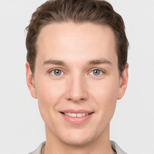 Joyful white young-adult male with short  brown hair and grey eyes