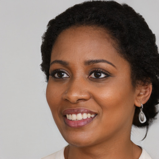 Joyful black young-adult female with long  black hair and brown eyes