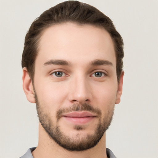 Joyful white young-adult male with short  brown hair and grey eyes