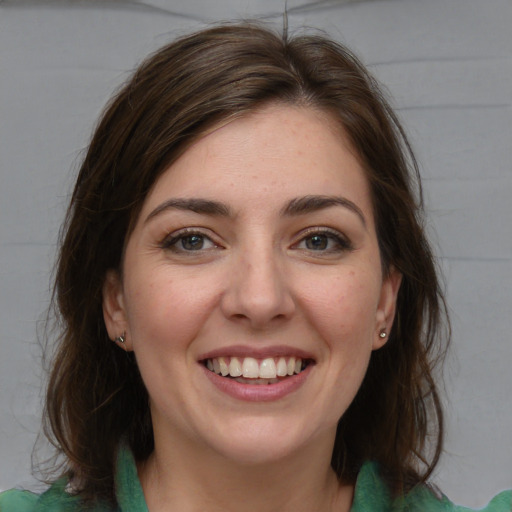 Joyful white young-adult female with medium  brown hair and grey eyes