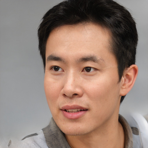 Joyful asian young-adult male with short  brown hair and brown eyes