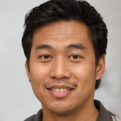 Joyful asian young-adult male with short  brown hair and brown eyes