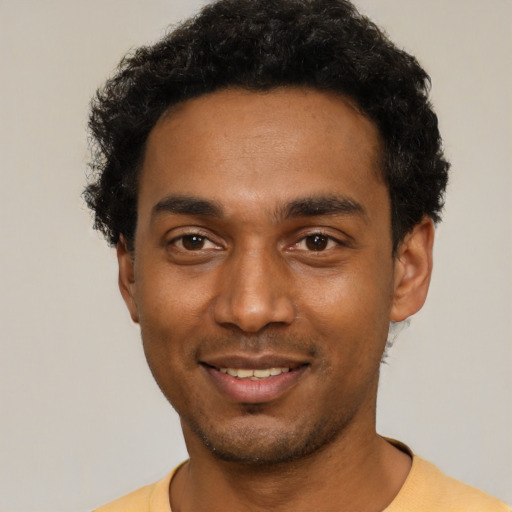 Joyful black young-adult male with short  black hair and brown eyes