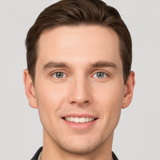 Joyful white young-adult male with short  brown hair and grey eyes