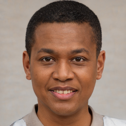 Joyful black young-adult male with short  brown hair and brown eyes