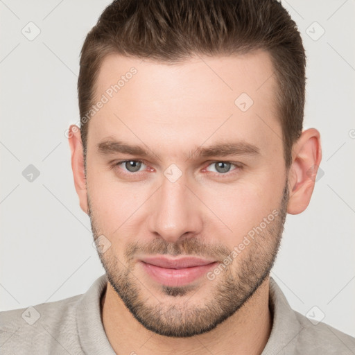 Joyful white young-adult male with short  brown hair and grey eyes