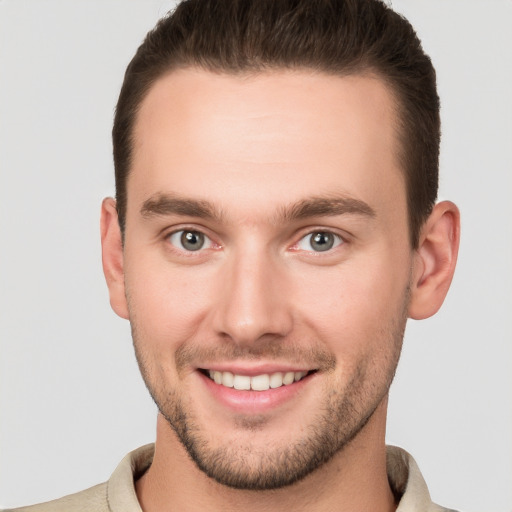 Joyful white young-adult male with short  brown hair and grey eyes