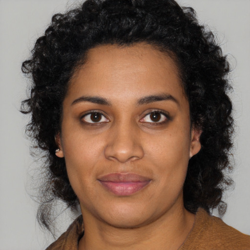 Joyful black young-adult female with long  black hair and brown eyes
