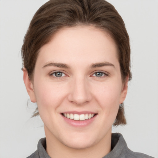 Joyful white young-adult female with medium  brown hair and grey eyes