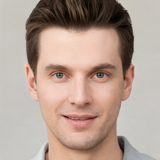 Joyful white young-adult male with short  brown hair and grey eyes