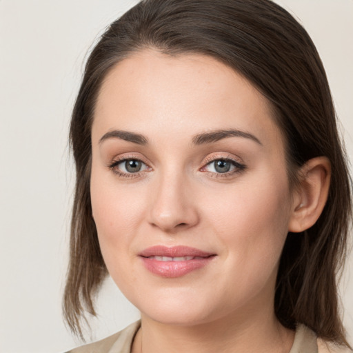 Joyful white young-adult female with medium  brown hair and grey eyes