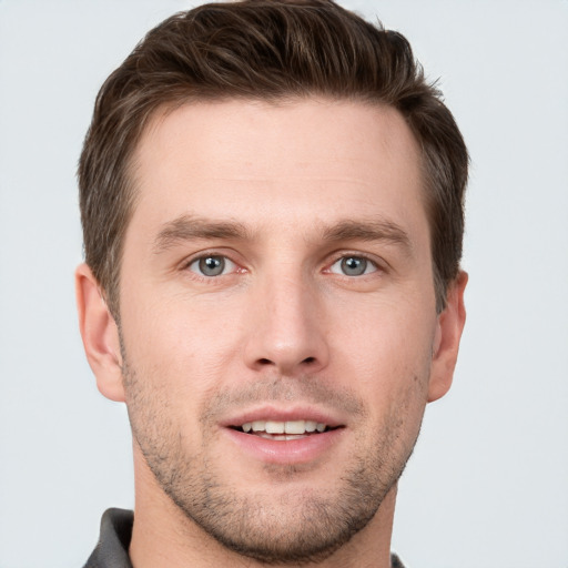 Joyful white young-adult male with short  brown hair and grey eyes