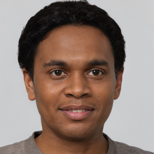 Joyful black young-adult male with short  black hair and brown eyes