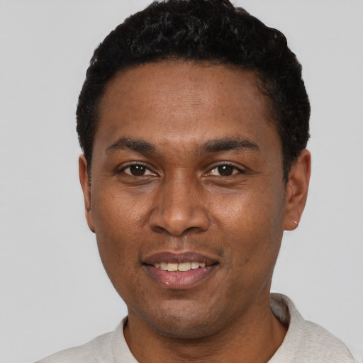 Joyful black young-adult male with short  black hair and brown eyes