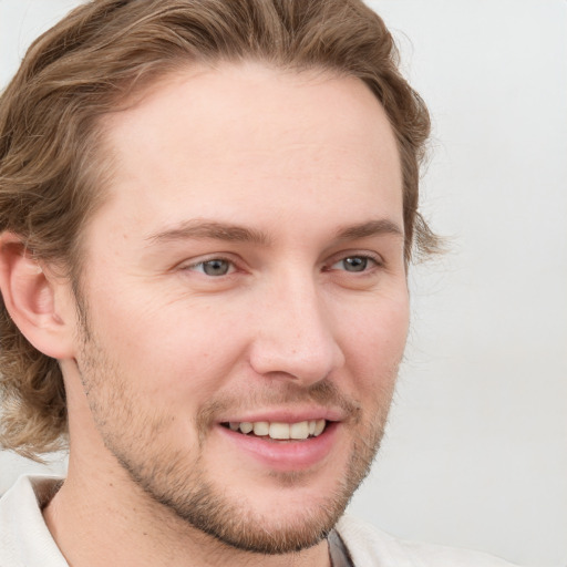 Joyful white young-adult male with short  brown hair and blue eyes