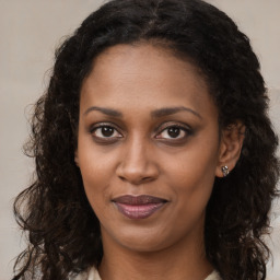 Joyful black young-adult female with long  brown hair and brown eyes