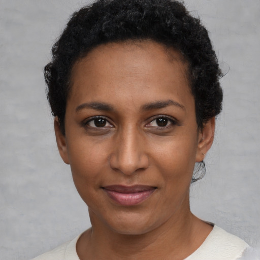 Joyful black young-adult female with short  black hair and brown eyes