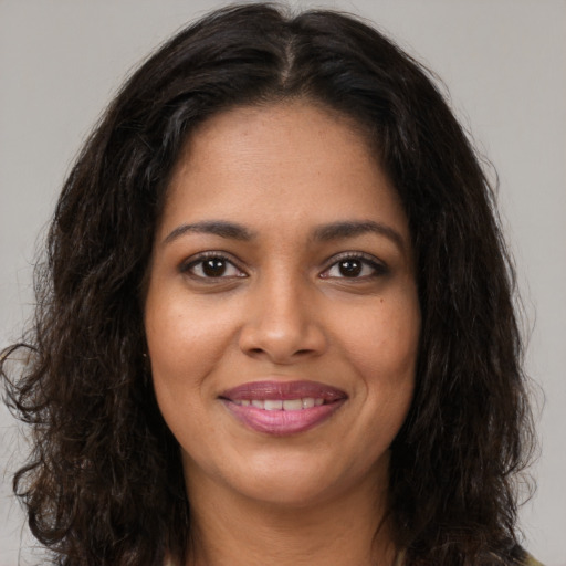 Joyful black young-adult female with long  brown hair and brown eyes