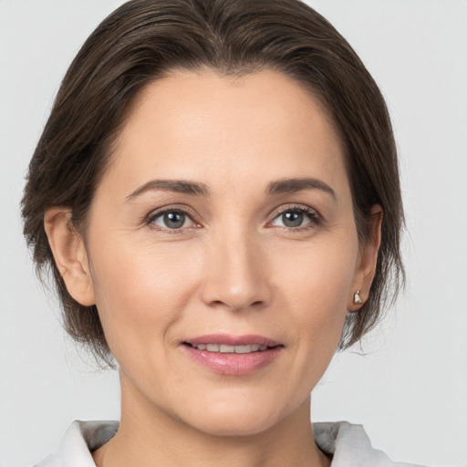 Joyful white young-adult female with medium  brown hair and grey eyes