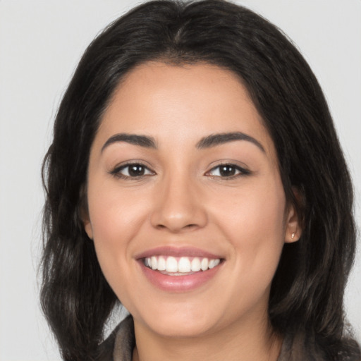 Joyful latino young-adult female with long  brown hair and brown eyes