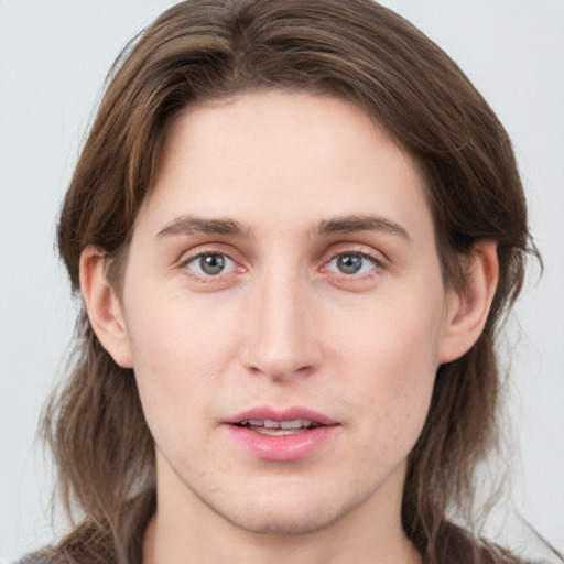 Joyful white young-adult male with long  brown hair and grey eyes