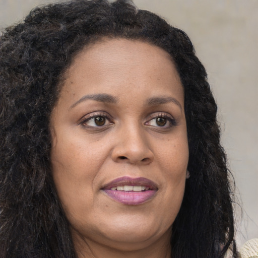 Joyful black adult female with long  brown hair and brown eyes