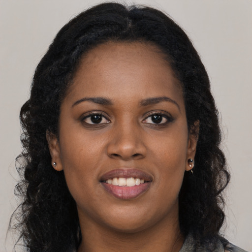 Joyful black young-adult female with long  brown hair and brown eyes