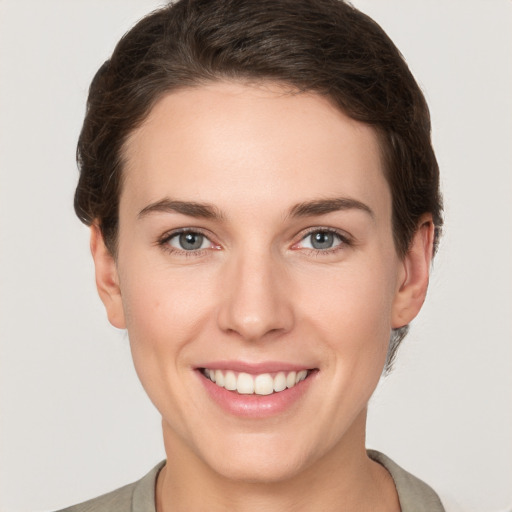 Joyful white young-adult female with short  brown hair and grey eyes