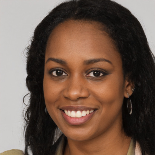 Joyful black young-adult female with long  black hair and brown eyes
