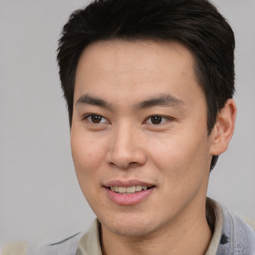 Joyful asian young-adult male with short  brown hair and brown eyes