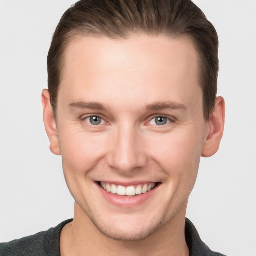 Joyful white young-adult male with short  brown hair and grey eyes