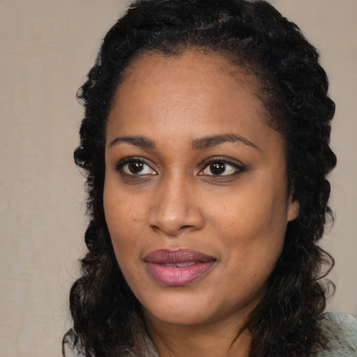 Joyful black young-adult female with long  black hair and brown eyes