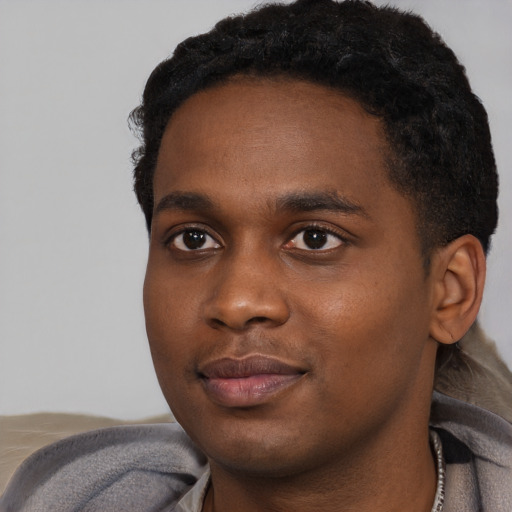 Joyful black young-adult male with short  black hair and brown eyes