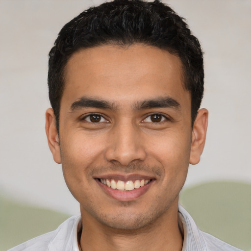 Joyful latino young-adult male with short  black hair and brown eyes