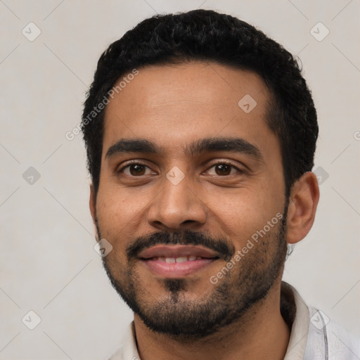 Joyful latino young-adult male with short  black hair and brown eyes