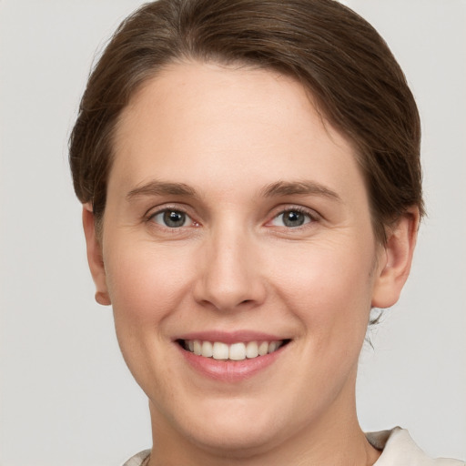 Joyful white young-adult female with short  brown hair and grey eyes