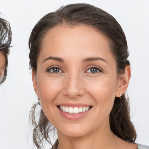 Joyful white young-adult female with medium  brown hair and grey eyes