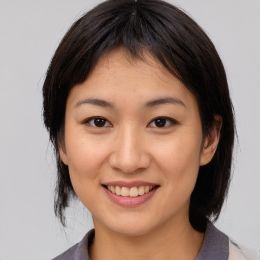 Joyful asian young-adult female with medium  brown hair and brown eyes