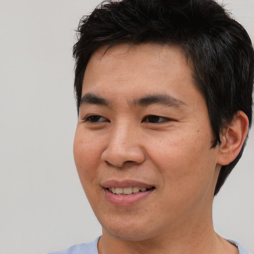 Joyful asian young-adult male with short  black hair and brown eyes