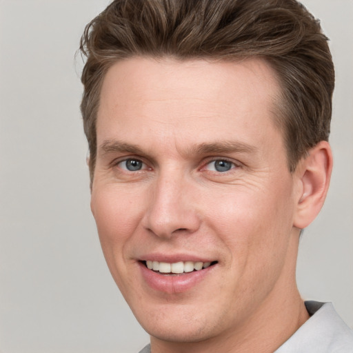 Joyful white young-adult male with short  brown hair and grey eyes