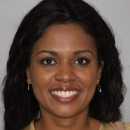 Joyful black young-adult female with long  brown hair and brown eyes