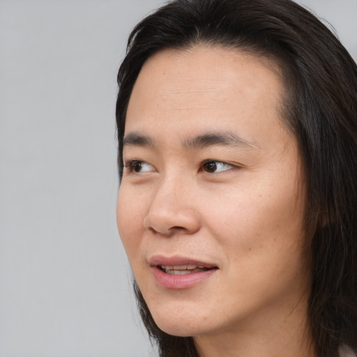 Joyful asian young-adult male with long  brown hair and brown eyes