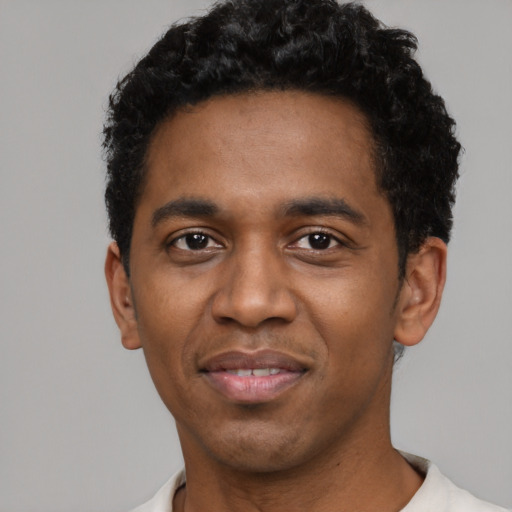 Joyful black young-adult male with short  black hair and brown eyes